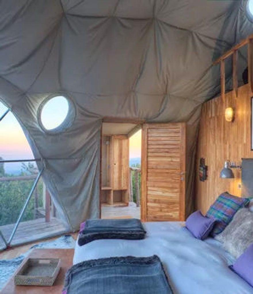 Luxury safari tent perched on wooden platform overlooking Tanzania savanna at sunset, featuring private deck and canvas canopy