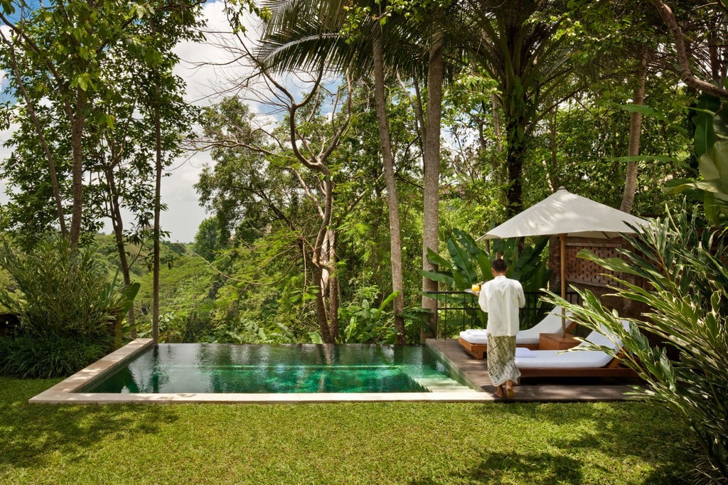 Infinity pool overlooking lush Balinese jungle at COMO Uma Ubud resort, with stone walls and tropical gardens beneath clear blue sky