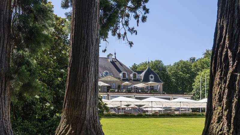 Elegant five-star lakeside hotel in Geneva with Belle Époque architecture, classic white facade and ornate balconies overlooking Lake Geneva