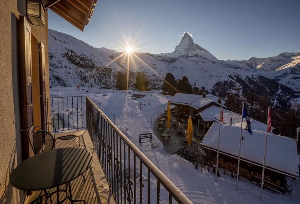 Luxury mountain lodge with wooden balconies nestled in snow-capped Swiss Alps, featuring panoramic views and traditional architecture