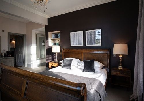 Elegant boutique hotel room with plush white bedding, large windows, contemporary furnishings, and soft neutral tones at Bainbridge's luxurious countryside retreat