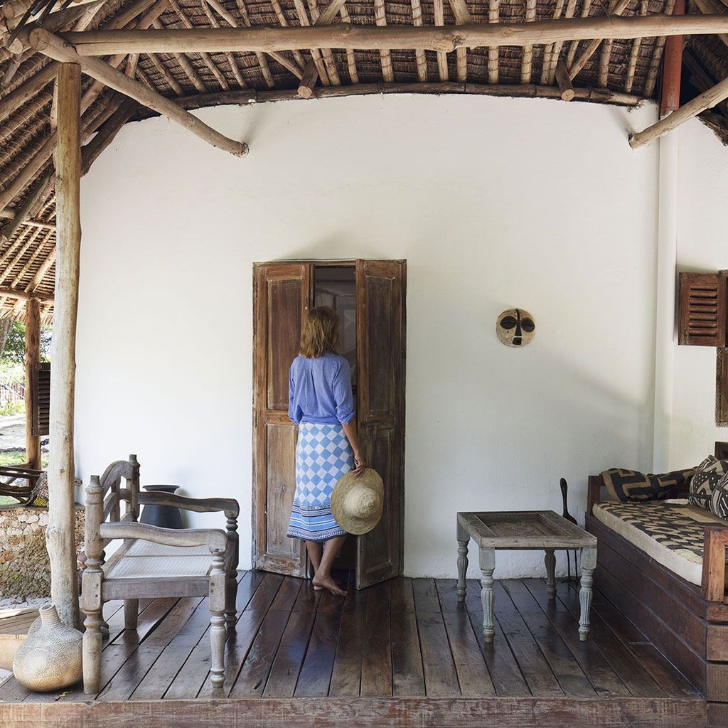 Luxury beachfront cottage with white linen, wooden furniture, and panoramic views of turquoise Indian Ocean at Kinondo Kwetu resort, Kenya