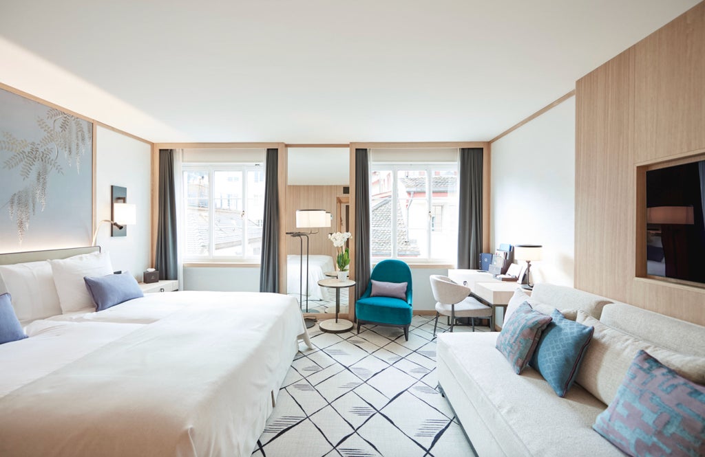 Spacious two-bedroom suite with modern furnishings, wooden floors, and city views through large windows in Storchen Hotel, Switzerland