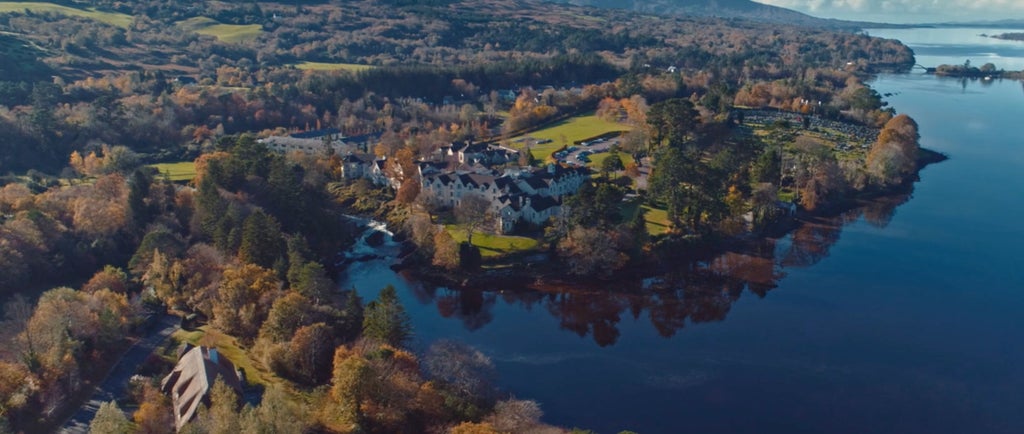 Luxurious stone lodge nestled among vibrant gardens beside cascading waterfalls, featuring elegant Georgian architecture and mountain views