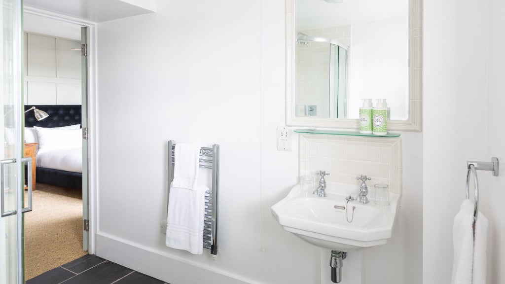 Elegant boutique hotel room with modern shower, soft neutral tones, crisp white linens, and minimalist design in a UK urban accommodation setting