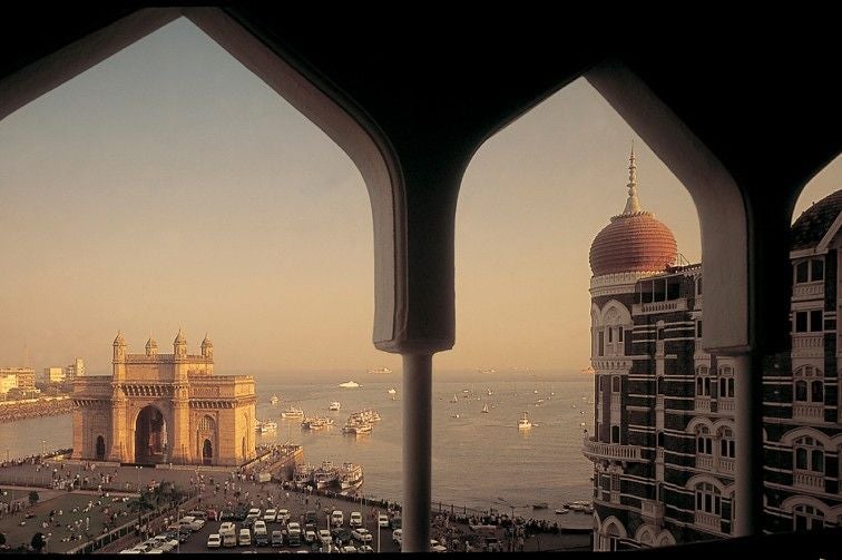 Historic Taj Mahal Palace Hotel in Mumbai features grand Indo-Gothic architecture, central red dome, waterfront location and ornate facades