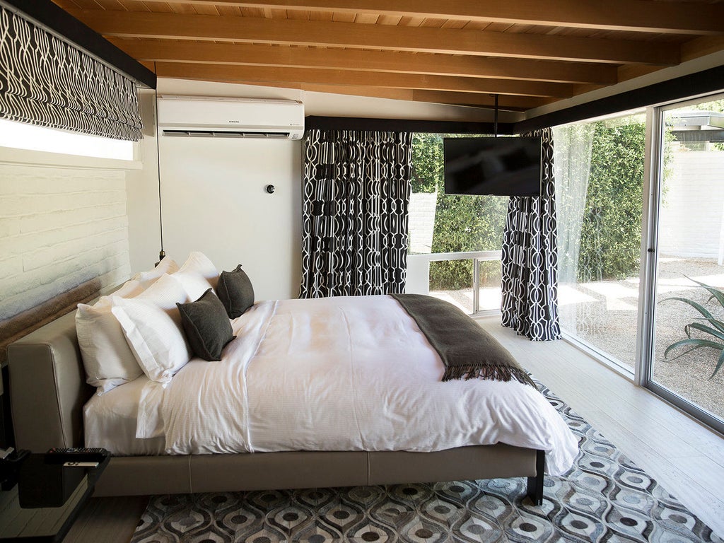 Modern luxury hotel in Palm Springs featuring a stark white exterior, expansive pool area, and palm trees against a desert mountain backdrop