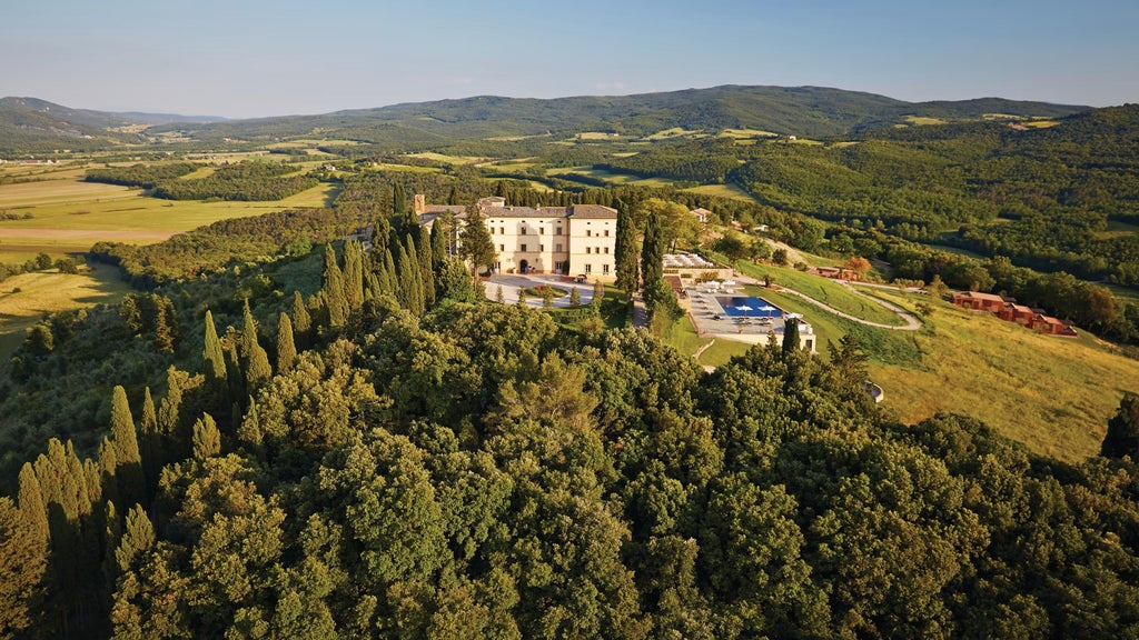 Tuscan luxury hotel with stone castle towers and cypress trees overlooking rolling hills at sunset, terra cotta rooftops visible