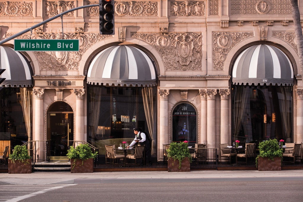 Grand, Mediterranean-style Four Seasons Beverly Wilshire Hotel with ornate architecture, palm-lined driveway and luxury valet entrance at dusk