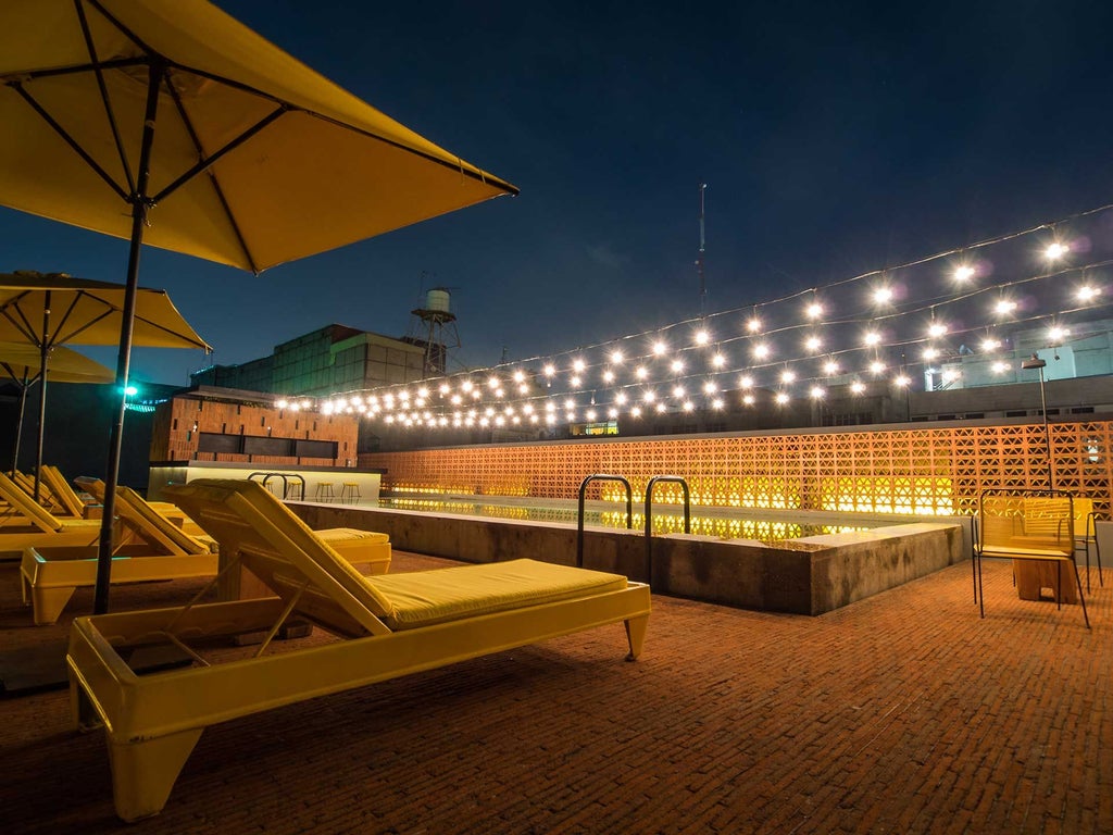 Elegant colonial-style hotel lobby with high ceilings, rustic stone walls, vintage furniture, and warm lighting, showcasing urban Mexican architectural heritage