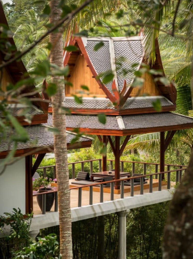 Spacious tropical pavilion suite with king bed, dark wood accents, private terrace, and ocean views through floor-to-ceiling windows