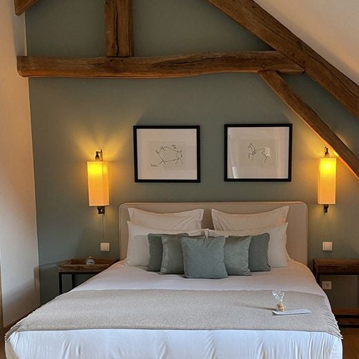 Elegant French hotel room with soft, muted colors, plush bedding, and vintage decor in the luxurious Manoir de Surville, showcasing a cozy, intimate atmosphere