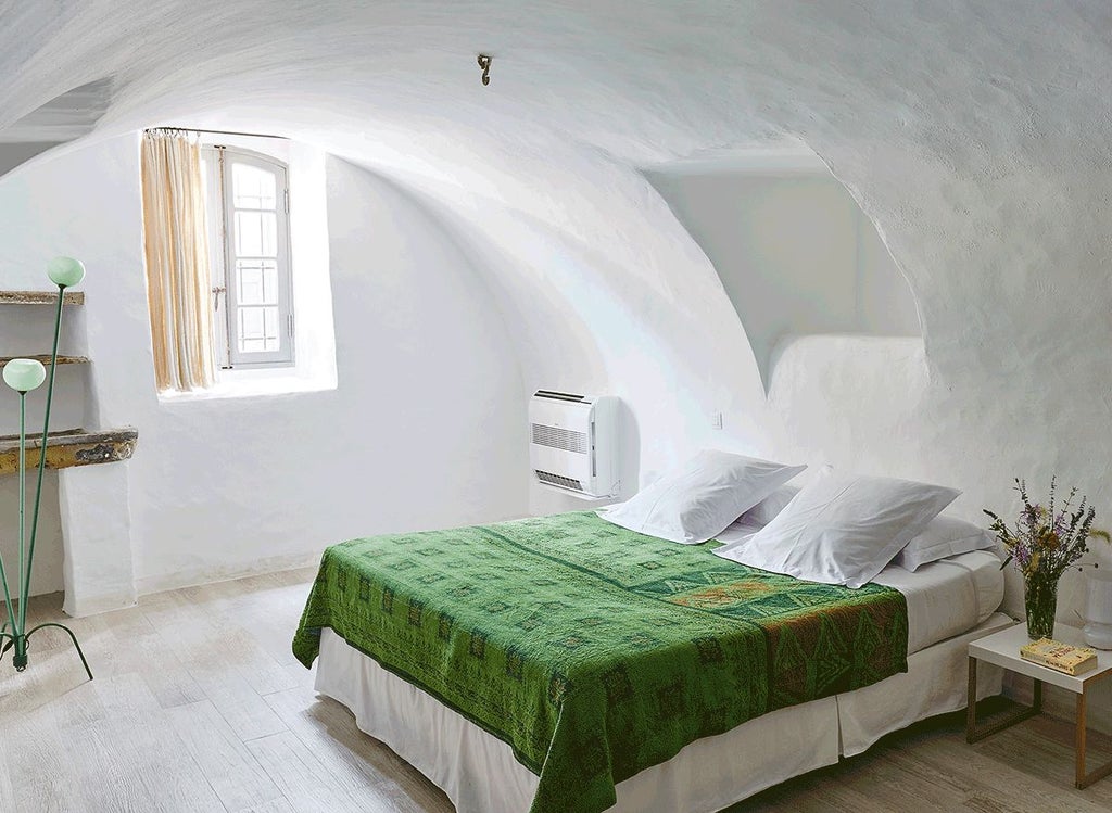 Elegant limestone-walled hotel suite with soft neutral tones, antique furnishings, and large windows overlooking French countryside landscape