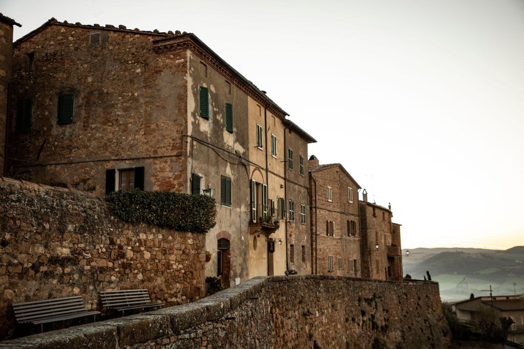 Elegant boutique hotel facade in Tuscany, stone walls, arched windows, rustic chic design with modern minimalist touches, warm golden sunlight