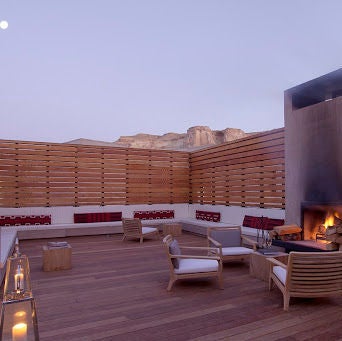 Modern desert resort with cubic concrete architecture seamlessly blending into red rock formations, featuring an infinity pool