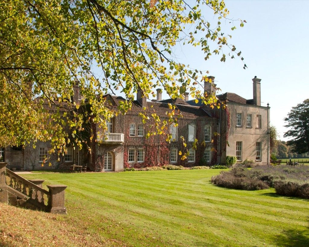 Elegant Georgian country house hotel with manicured gardens, grand facade, and tree-lined driveway nestled in scenic Wiltshire countryside