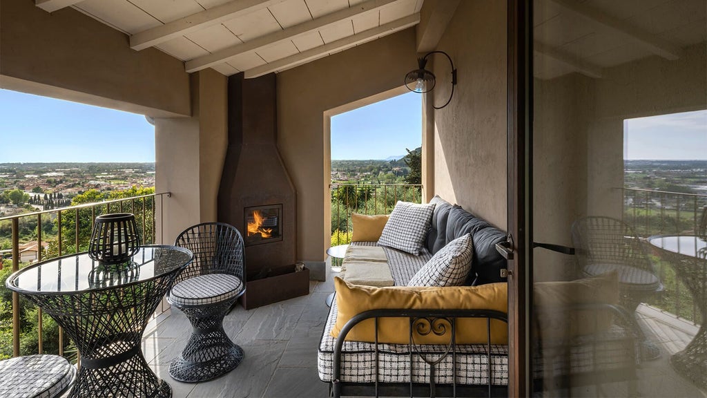 Elegant Tuscan-style hotel room with soft white linens, rustic wooden furniture, and panoramic countryside views near Lucca, Italy