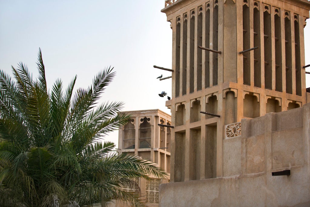 Luxurious beachfront resort with white Mediterranean-style architecture, palm trees and infinity pool overlooking Jumeirah Beach