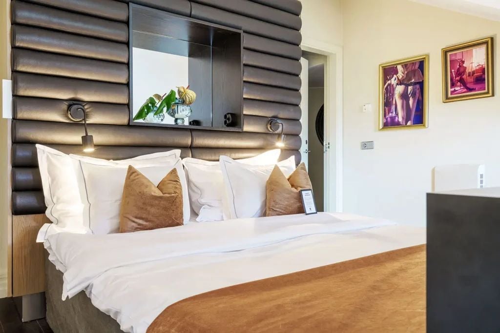 Elegant Scandinavian-style deluxe hotel room with plush king bed, designer furniture, warm neutral tones, and sophisticated urban luxury in scenset Hotel