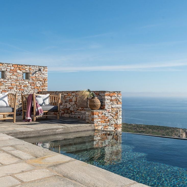 Luxurious whitewashed Cycladic hotel with infinity pool overlooking azure Aegean Sea, featuring minimalist architecture and stunning sunset views in Sifnos, Greece.