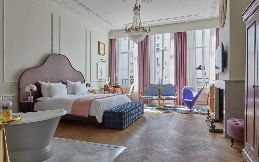 Elegant suite in historic Amsterdam canal house featuring moody blue walls, luxurious gold accents, and modern furnishings with canal views