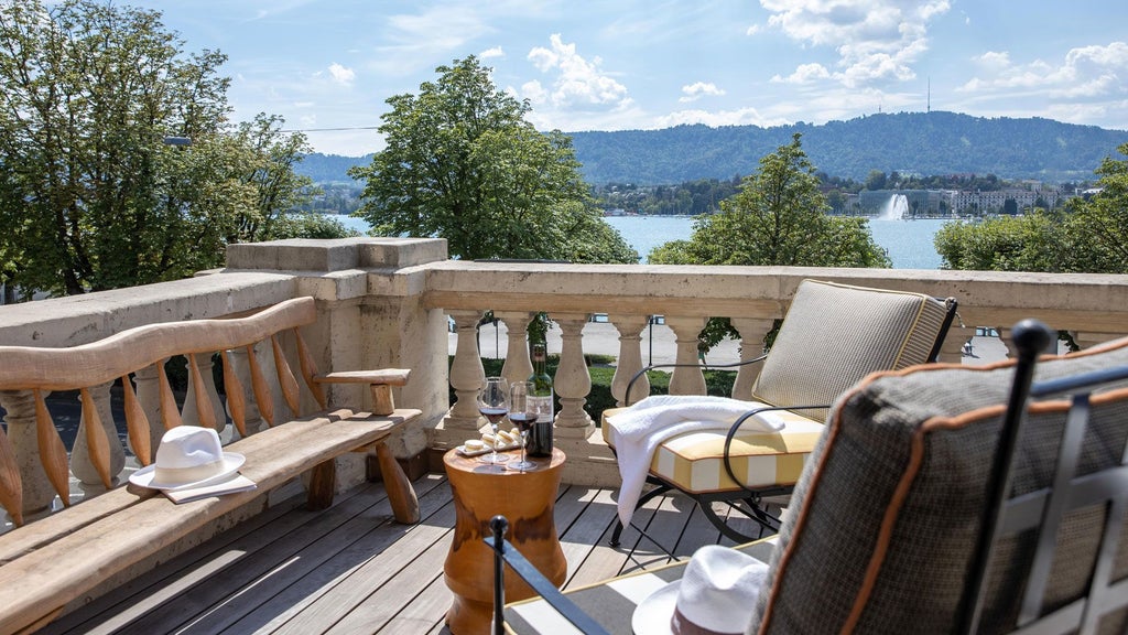 Luxurious lakeside hotel with modern Swiss design, large windows overlooking Zurich Lake, elegant white facade, and lush surrounding landscape at golden hour.