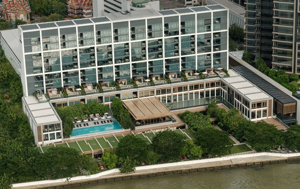 Elegant riverside suite at Capella Bangkok with floor-to-ceiling windows, plush king bed, marble bath and views of the Chao Phraya River