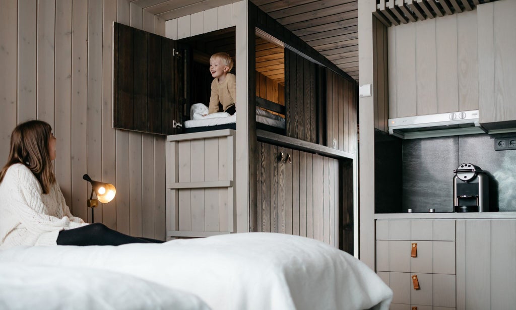 Modern Finnish suite with panoramic windows overlooking snowy forest, minimalist Nordic design, cozy wood interior, and white bedding with scenic Arctic landscape view