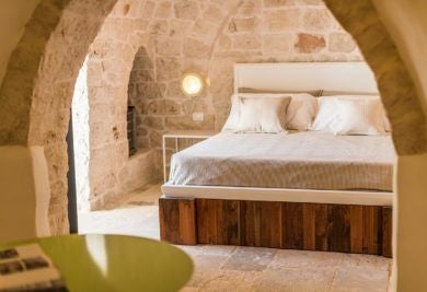 Rustic stone suite with vaulted ceiling at Borgo Canonica, featuring minimalist decor, warm lighting, and traditional Apulian architectural elements