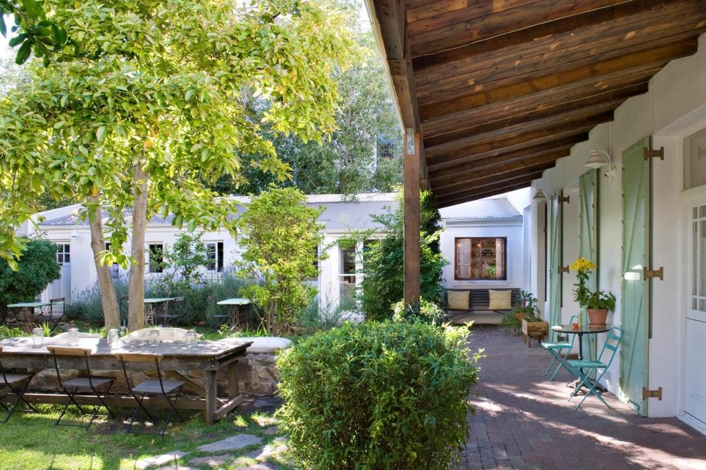 French colonial guesthouse with lush garden courtyard, white-washed walls, vintage shutters and elegant wrought iron balcony details