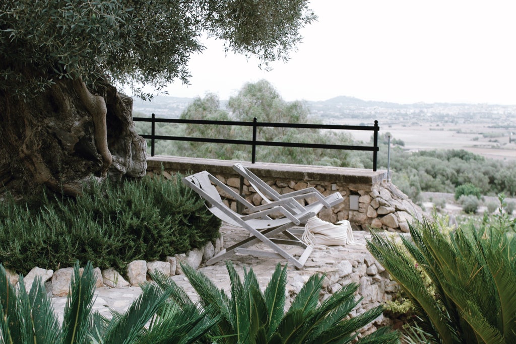 Historic Spanish village nestled on hilltop with iconic stone windmill tower, golden-hued buildings, and winding cobblestone streets at sunset