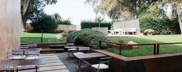 Modern minimalist loft with sleek wood furnishings, large windows overlooking Tuscan landscape, soft natural light creating an elegant boutique hotel ambiance