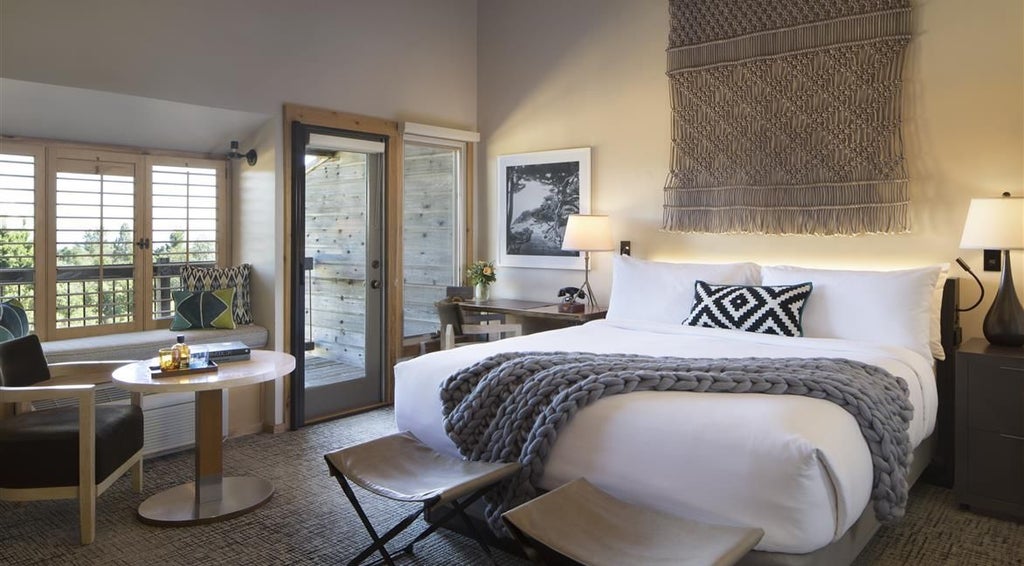 Luxurious guestroom at Ventana Big Sur with elegant wooden furnishings, crisp white linens, and panoramic views of coastal California wilderness