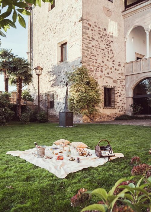 Historic stone castle hotel perched on Italian mountainside, featuring elegant balconies and terraces with panoramic views of Alpine valleys