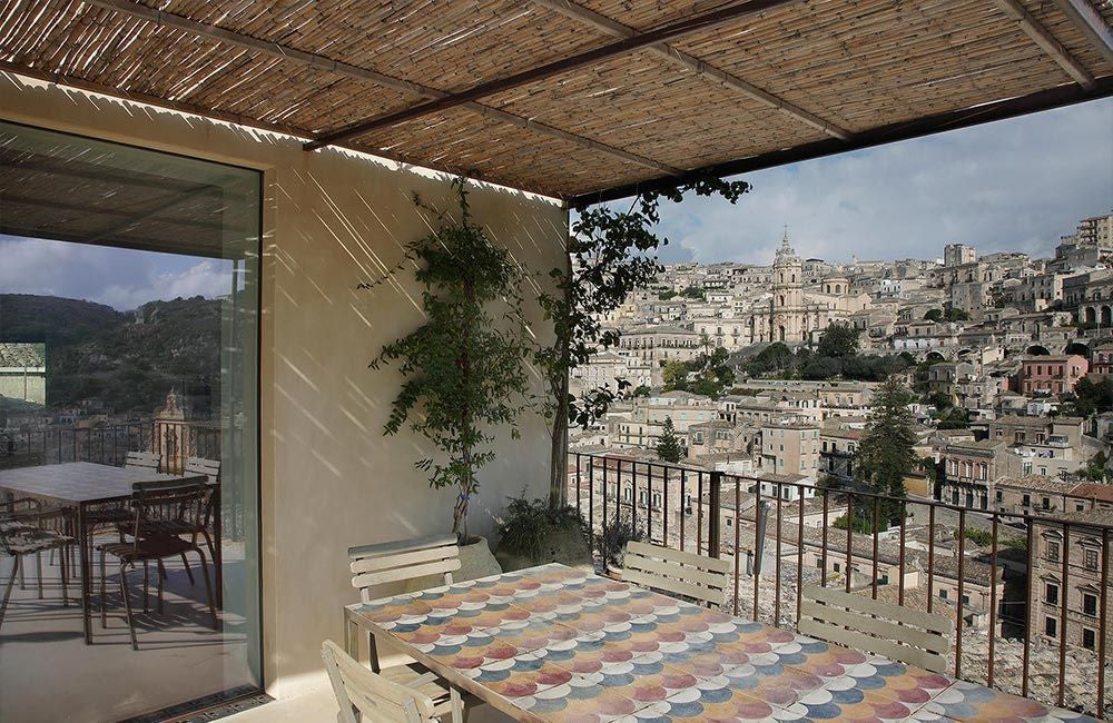 Elegant stone-walled boutique hotel nestled in Sicilian landscape, rustic architectural details framed by lush greenery and Mediterranean sunlight