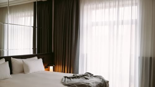 Elegant junior suite at Almanac X Alcron in Prague, featuring sophisticated contemporary design with plush bedding and panoramic city view windows