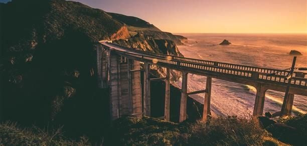 Luxurious hot tub suite overlooking dramatic coastal landscape, with modern wooden design and panoramic views of rugged Big Sur wilderness