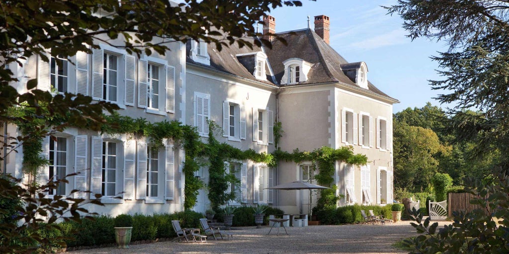 Elegant stone château with manicured gardens, reflecting soft evening light against French countryside backdrop, showcasing refined architectural symmetry and luxurious landscaping