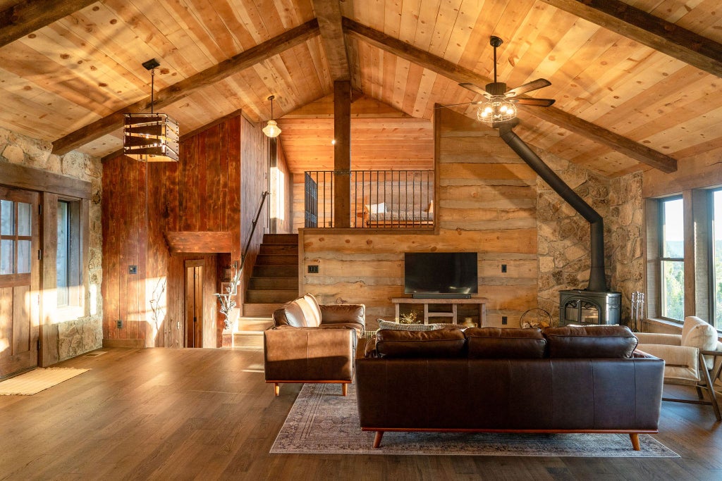 Rustic lodge bedroom with wooden furnishings, plush bedding, large windows overlooking scenic mountain landscape at Scenset Mountain Ranch