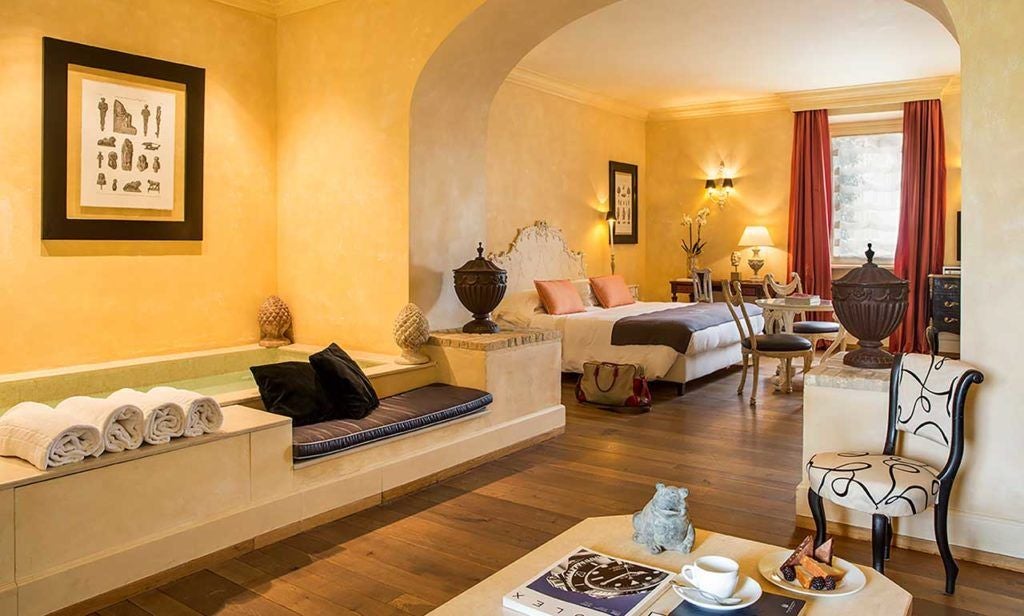 Elegant Superior Room at L'Andana, Tuscany, with soft neutral tones, plush bed, traditional wooden furniture, and soft natural light.