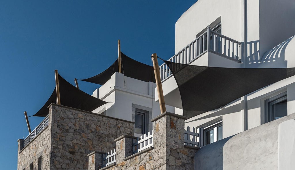 Luxurious white-washed Greek suite with blue accents, overlooking scenic Aegean Sea, traditional Cycladic architecture with elegant balcony and sunlight