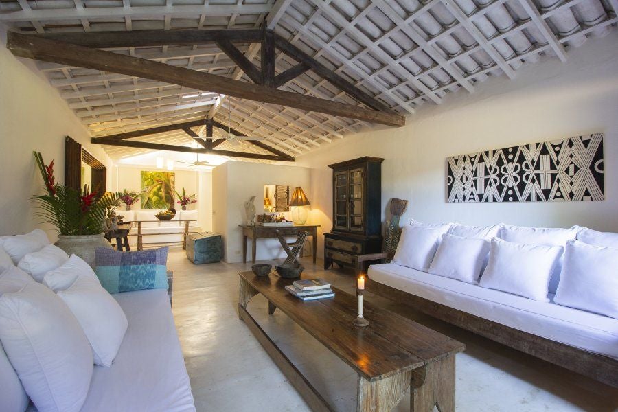 Luxurious Brazilian hotel room with rustic wooden furniture, soft white linens, and tropical botanical accents at UXUA Casa Hotel and Spa in Trancoso