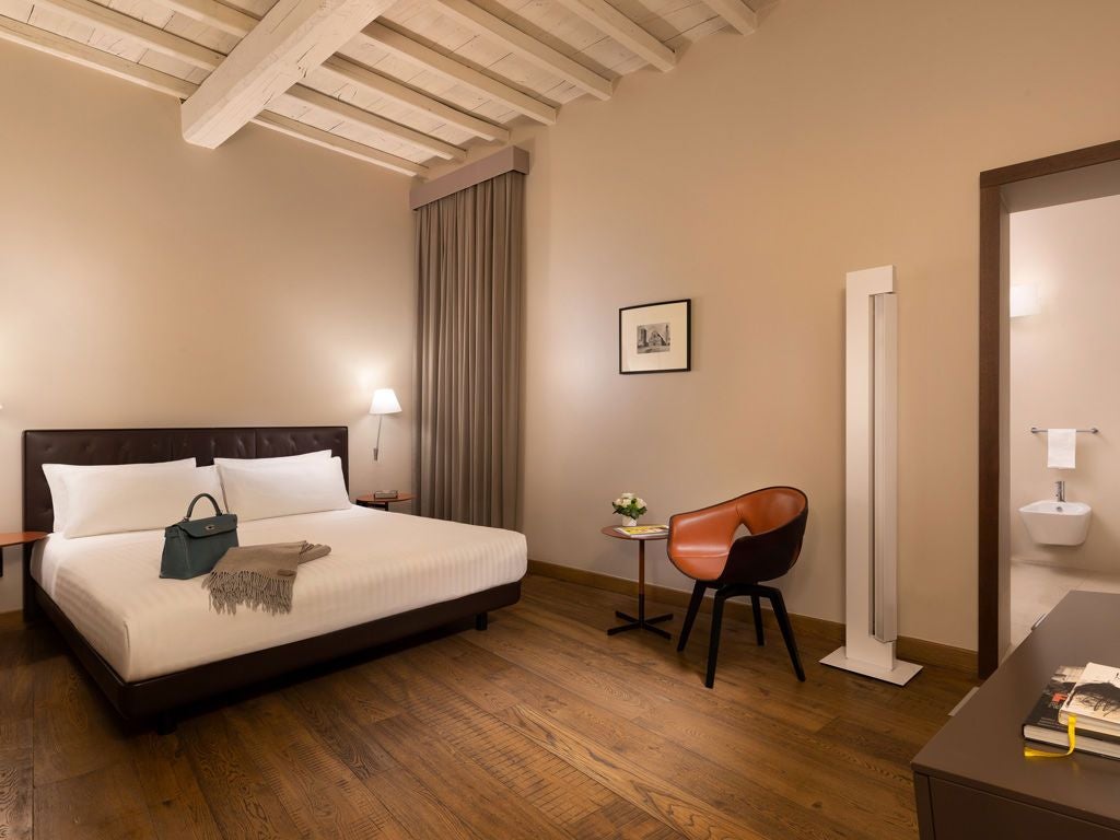 Elegant boutique hotel room in historic Italian palazzo, featuring plush white bedding, marble accents, and soft ambient lighting near scenic windows