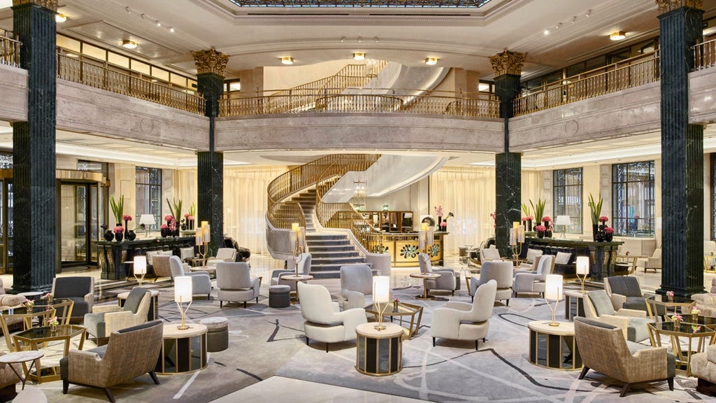 Elegant Four Seasons Madrid facade with ornate Beaux-Arts architecture, grand arched windows, and classic stone balconies lit by warm evening light