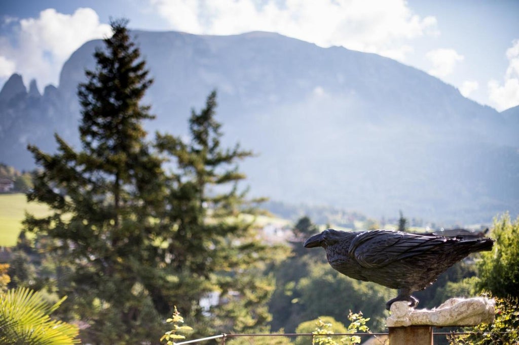 Historic stone castle-hotel nestled in Italian Alps with medieval tower, luxury terrace dining area, and panoramic mountain views