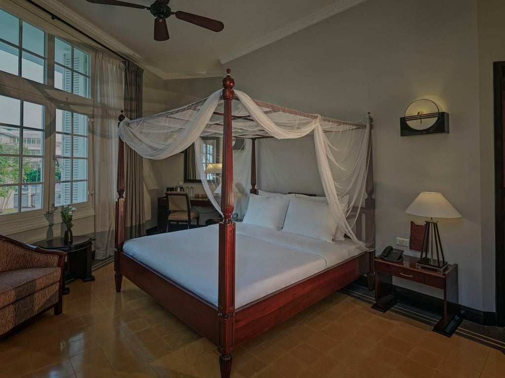 Elegant colonial-style deluxe hotel room at Azerai La Residence, Hue, featuring vintage furnishings, rich wooden floors, and traditional Vietnamese architectural details