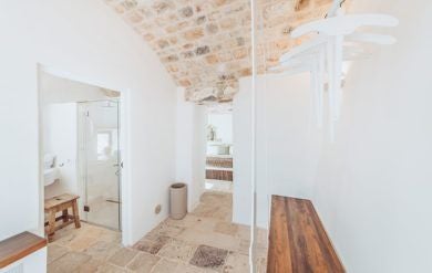 Rustic stone Deluxe Lamia suite at Borgo Canonica, showcasing traditional Italian architecture with elegant white-washed walls and minimalist design.