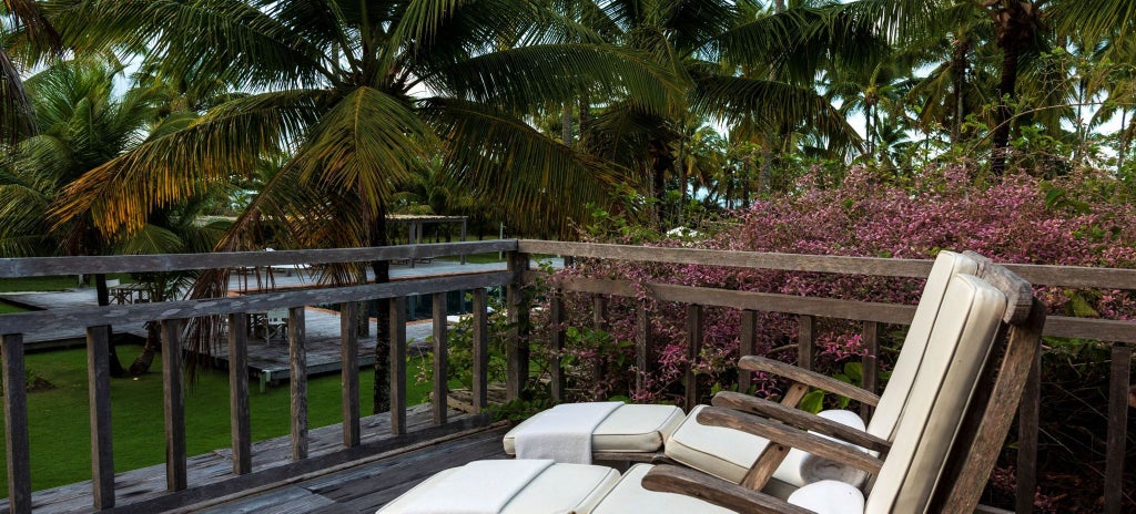 Spacious luxury suite with elegant wooden furnishings, soft neutral tones, and large windows overlooking lush Brazilian countryside at Fazenda São Francisco do Corumbau