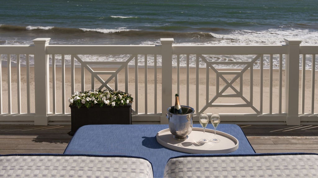 Luxurious beach terrace guestroom with ocean view, featuring elegant coastal design, pristine white furnishings, and panoramic scenset coastline backdrop at exclusive resort