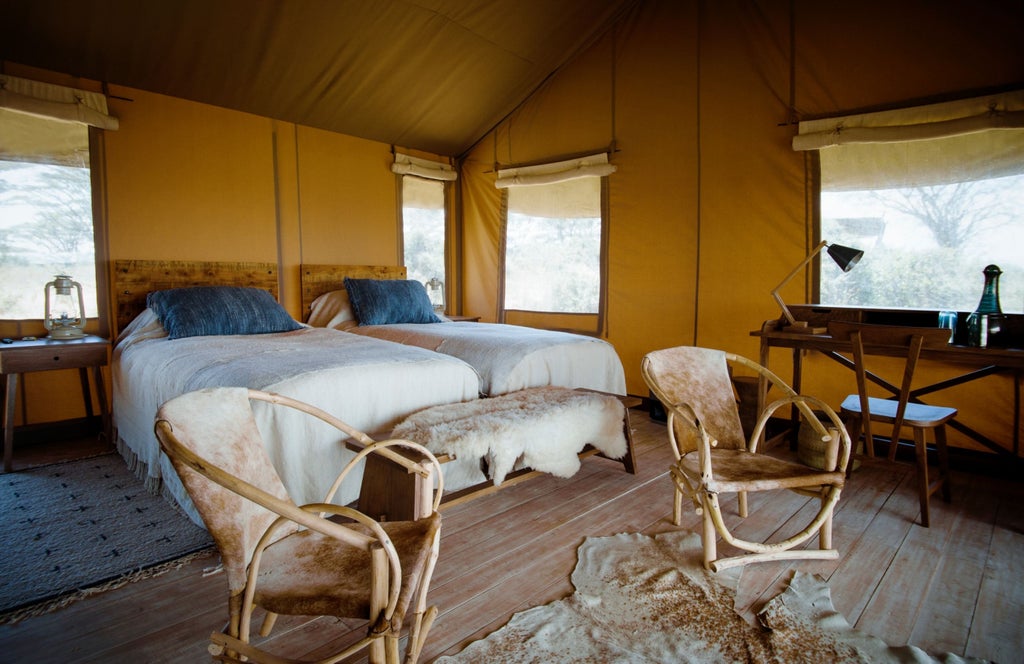 Luxurious safari camp tent with canvas walls overlooking the vast Ngorongoro Crater, featuring elegant outdoor terrace and scenic backdrop